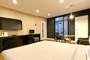 a bedroom with a bed and a desk and a tv at Hotel Home in Busan +24 photos