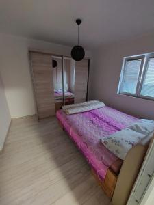 1 dormitorio con 1 cama con sábanas moradas y espejo en Apartman San en Brčko