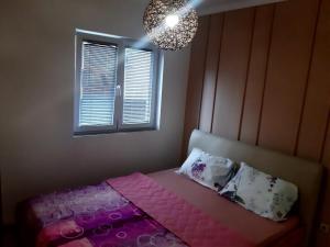 sypialnia z różowym łóżkiem i żyrandolem w obiekcie Apartman San w mieście Brczko