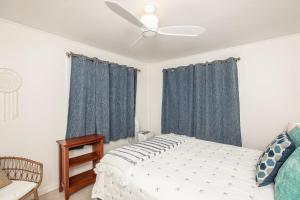 una camera da letto con un letto con tende blu e un ventilatore a soffitto di Hawaii Oceanfront Beach House Paradise on the Beach Family Activities a Haleiwa