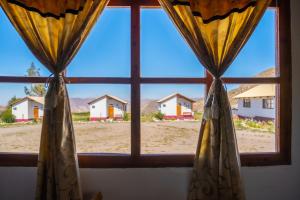 d'une fenêtre avec vue sur les maisons au loin. dans l'établissement La Chakana Lodge, à Putre