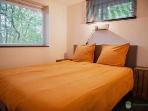 een slaapkamer met een bed met oranje lakens en een raam bij Charming 4-person holiday home on the edge of Leenderstrijp in the forest in Leende