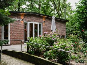 een stenen huis met een veranda en een paraplu bij Charming 4-person holiday home on the edge of Leenderstrijp in the forest in Leende