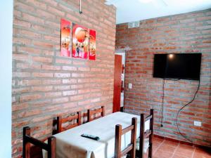 a room with a brick wall with a table and a tv at Signos de Merlo in Merlo