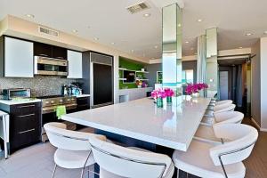 a kitchen with a large counter with white chairs at Crown Jewel in Mission Beach at Ocean Front Walk in San Diego