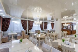 ein Restaurant mit weißen Tischen, Stühlen und Kronleuchtern in der Unterkunft Villa Nikoletta in Bukowel