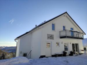 - un bâtiment blanc avec un balcon dans la neige dans l'établissement Appart-Hotel Harmonie, à Winterberg