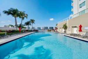a swimming pool at a hotel with chairs and palm trees at Waterfront luxury new apartment in Miami Beach
