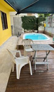 eine Terrasse mit Tisch und Stühlen und einem Pool in der Unterkunft Soares Acomodações in Itapema