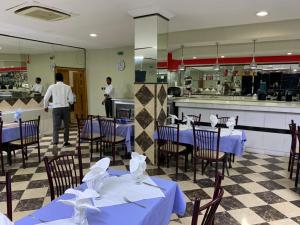 a restaurant with blue tables and chairs and a kitchen at Hotel Hayatt in Nouakchott