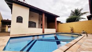 a swimming pool in front of a house at Piscina, Churrasqueira, Wi-Fi, SmartTv, 4dorm, Comércios na porta in Itanhaém