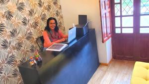 una mujer sentada en un escritorio con un portátil en Hotel Inti Quito, en Quito