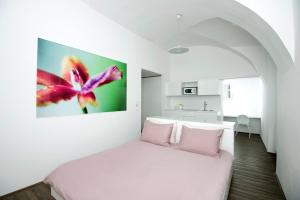 una camera da letto con un letto bianco e cuscini rosa di Galeria River a Lubiana