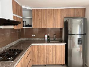una cucina con frigorifero in acciaio inox e mobili in legno di Travelu Guatape Apartamento a Guatapé