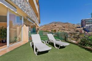 フエンヒロラにあるGarden apartment with sea view in Fuengirolaの山の景色を望むパティオ(白い椅子2脚付)
