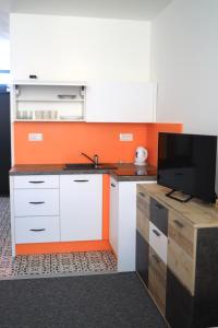 an orange and white kitchen with a tv on a counter at 2 REST 