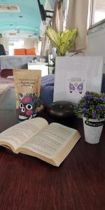 un libro abierto sentado en una mesa junto a las flores en Dreamcatcher House Bus Experience 2 en Sarchí