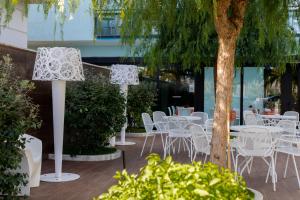 a patio with white chairs and tables and a tree at Hotel Continental in Tortoreto Lido