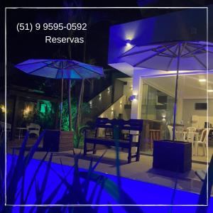 a house with a swimming pool with umbrellas in the night at Morada Summer Beach Beira Mar in Tramandaí