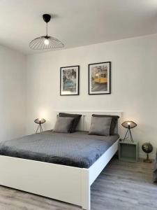 een witte slaapkamer met een bed en 2 lampen bij L’Adorable Gayant in Waziers