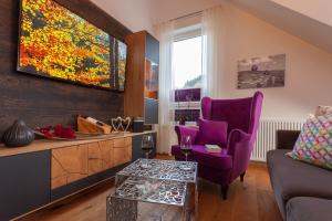 uma sala de estar com uma cadeira roxa e um sofá em Ferienwohnung Bergzauber 1 mit MeineCardPlus em Willingen