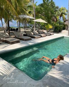 a woman laying in a swimming pool at a resort at Casa Las Gatas in Zihuatanejo