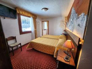 a hotel room with a bed and a table with a lamp at Apartments Suites LAC BLEU in Breuil-Cervinia