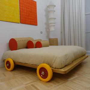 un lit avec des roues jaunes et rouges dans une pièce dans l'établissement MEA DOMUS Mergellina, à Naples