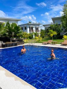 two men are swimming in a blue swimming pool at Red Picnic Hostel Panglao in Panglao Island +80 photos