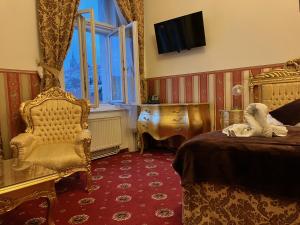 a bedroom with a bed and a chair and a television at Hotel Klarinn Prague Castle in Prague
