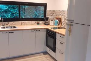 Una cocina con un refrigerador blanco y una ventana. en Ohana del bosque, en Mar del Plata