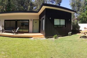 una pequeña casa negra con terraza y mesa en Ohana del bosque, en Mar del Plata