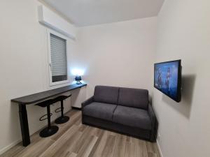 een kamer met een bank, een bureau en een televisie bij Nel Sole Superior in Bologna