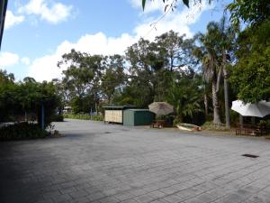 ein Parkplatz mit Tischen, Sonnenschirmen und Bäumen in der Unterkunft The Balnarring Motel in Balnarring