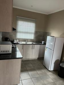 a kitchen with a white refrigerator and a sink at Ikhaya guesthouse2 in Pietermaritzburg
