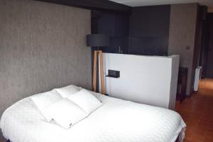 ein Bett mit weißen Laken und Kissen in einem Zimmer in der Unterkunft Studio au Moulin " Design Noir " Vue Unique in Dole