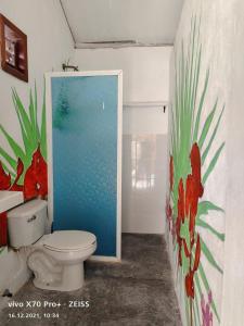 La salle de bains est pourvue de toilettes et d'une peinture murale. dans l'établissement Lunazul Eco-Cabaña Frente al Mar, à Mahahual