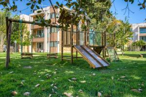 a playground in a park with a tree at Residence in Barra de São Miguel