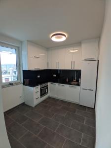 uma cozinha com armários brancos e piso em azulejo em Ika LuX apartmani 4* em Sjenica