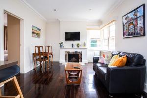 uma sala de estar com um sofá preto e uma lareira em Joli Light Filled Delight Close to the MCG em Melbourne