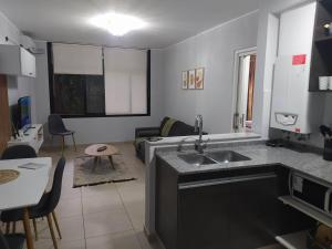 a kitchen with a sink and a living room at Lake 360 Apart Villa Carlos Paz in La Cuesta