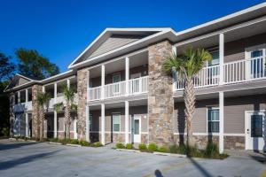 a large apartment building with palm trees in front at Lovely 4BR King Beds Steps To Beach And Pier F in Myrtle Beach