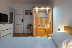 - une chambre avec un lit blanc et une télévision dans l'établissement Apartament Fiński z sauną, à Szklarska Poręba