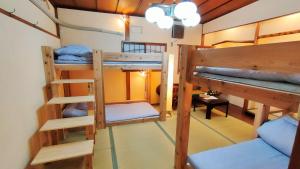 a room with three bunk beds and a table at Hostel Caranashi in Osaka