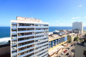 un edificio alto y blanco con el océano en el fondo en Vista Panorâmica, Conforto e Piscina à Beira-Mar, en Salvador