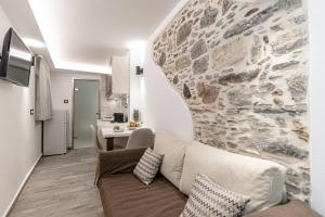 a living room with a couch and a stone wall at Mariet Naxos Spa & Suites in Naxos Chora