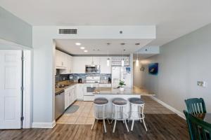a kitchen with white cabinets and a island with stools at Laketown Wharf! Sleeps 9 - Resort Beach Condo, Stunning Ocean Views! by Dolce Vita Getaways PCB in Panama City Beach