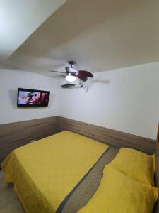 1 dormitorio con cama amarilla y ventilador de techo en R.1111 Estudio ejecutivo, práctico, en el centro., en Panamá
