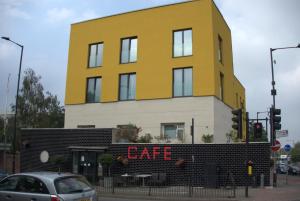 ein gelbes Gebäude mit einem Café-Schild davor in der Unterkunft Abbey Point Hotel in London