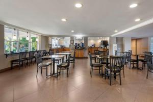a dining room with tables and chairs and a kitchen at Best Western Palm Beach Lakes in West Palm Beach